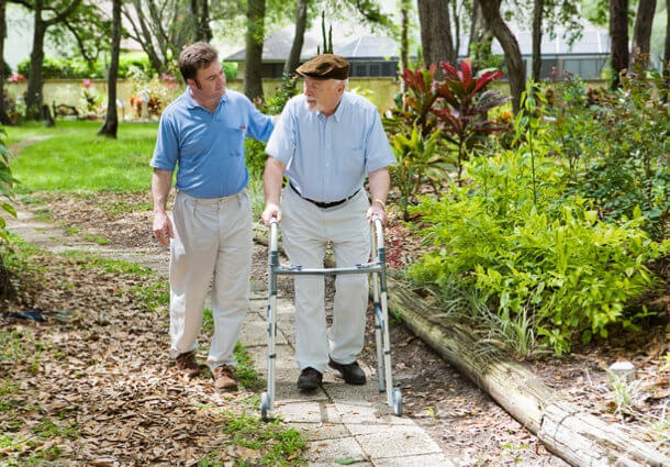 Elderly father and adult son out for a walk in the park.